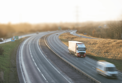 a uk main road seen at a distance with cars, a van and a hgv.